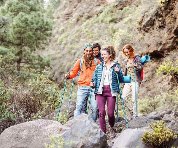Happy team friends doing trekking excursion on mountains - Group young tourists hiking and exploring the wild nature - Trekker, hike sport and travel people concept